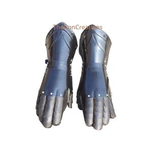May include: Pair of black metal gauntlets. The gauntlets are made of overlapping metal plates and are designed to protect the hands and wrists. The gauntlets have a dark, reflective finish and are likely part of a suit of armor.