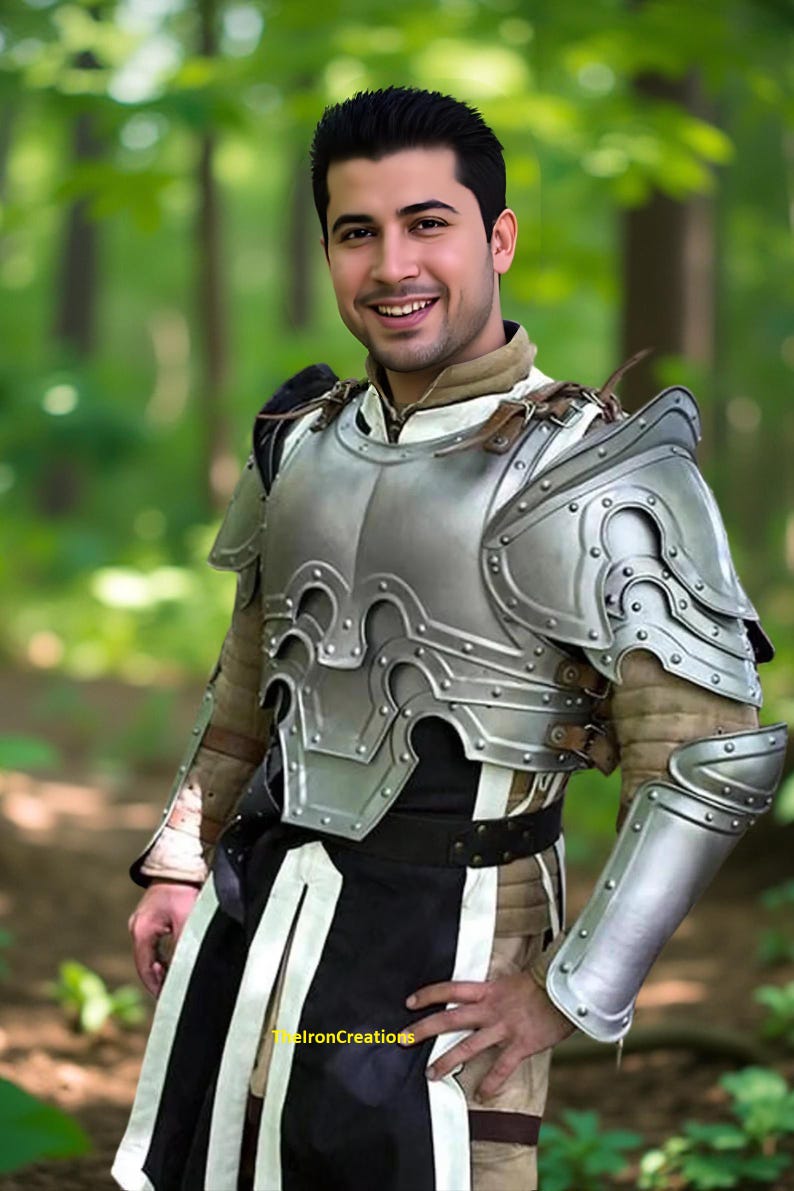 May include: A silver-colored medieval armor set with intricate detailing, including a breastplate, shoulder guards, and arm protection. The armor is worn over a brown and black garment. The image is set in a forest.