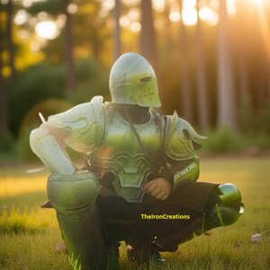 May include: A person wearing a green and silver medieval-style armor set, including a helmet, chest plate, and leg guards. The armor is detailed with rivets and a cross design on the helmet. The image is set outdoors in a grassy area.