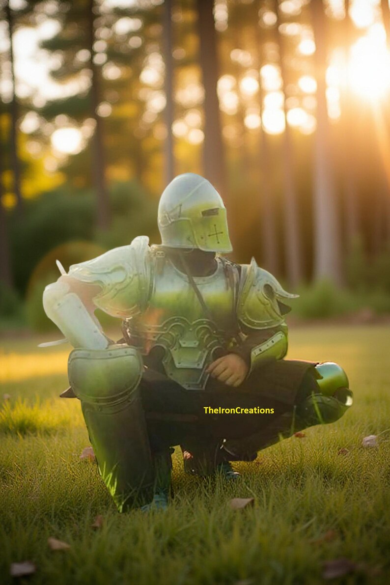 May include: A person wearing a green and silver medieval-style armor set, including a helmet, chest plate, and leg guards. The armor is detailed with rivets and a cross design on the helmet. The image is set outdoors in a grassy area.