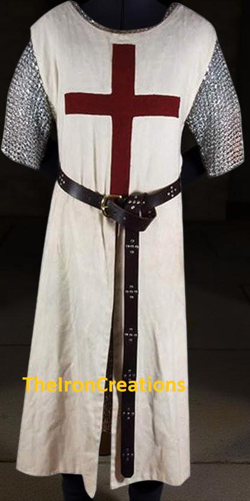 May include: Cream-colored medieval tunic with a large burgundy cross on the chest. The tunic features chainmail sleeves and a brown leather belt. A matching leather belt with decorative rivets cinches the waist. The text "TheIronCreations" is visible.