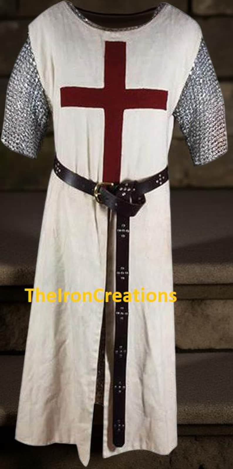 May include: Cream-colored medieval tunic with a large red cross on the chest. The tunic has chainmail sleeves and a black leather belt. The text "TheIronCreations" is visible on the bottom.