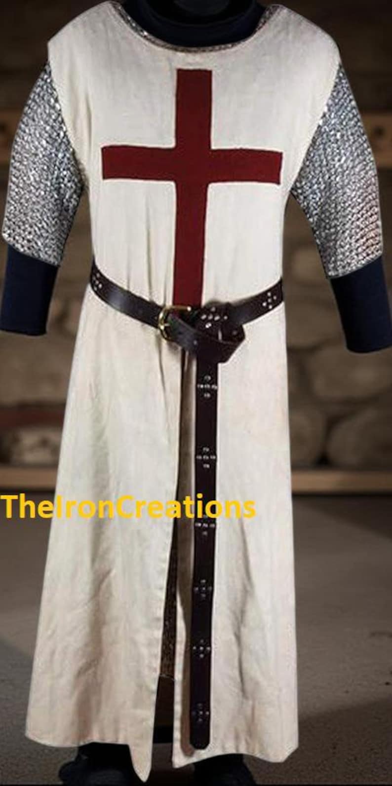 May include: Cream-colored medieval tunic with a large red cross on the front. The tunic has chainmail sleeves and a brown leather belt. The text "TheIronCreations" is visible on the lower left side.