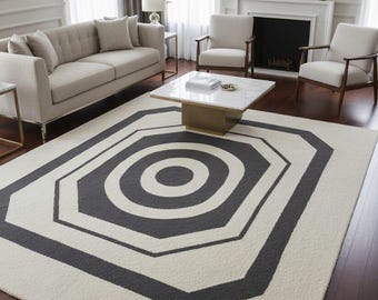 Puede incluir: Una alfombra grande de color crema con un diseño geométrico en gris antracita. La alfombra presenta una serie de octágonos y círculos concéntricos, creando un patrón gráfico moderno. La alfombra está colocada sobre un suelo de madera oscura en un salón.