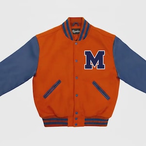 May include: Orange and blue varsity jacket with the letter "M" on the chest. The jacket has blue sleeves, a blue collar, and blue and orange striped cuffs and hem. The jacket has a button-up front and two front pockets.