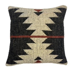 May include: Square decorative pillow with a geometric pattern. The pillow features a black and cream-colored design with a horizontal red stripe. The pattern is a repeating zig-zag design. The pillow is made of a woven fabric.