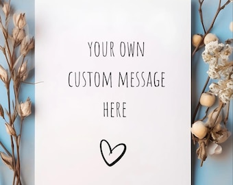 May include: A white card with the text "YOUR OWN CUSTOM MESSAGE HERE" and a heart symbol. The card is surrounded by dried floral arrangements against a light blue background.