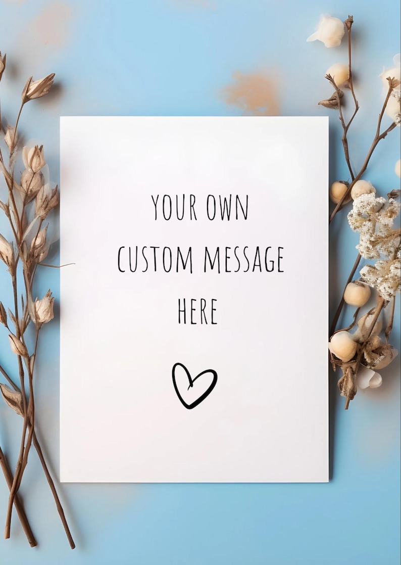 May include: A white card with the text "YOUR OWN CUSTOM MESSAGE HERE" and a heart symbol. The card is surrounded by dried floral arrangements against a light blue background.