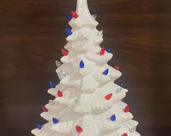 Patriotyczna, ceramiczna, biała choinka z gwiazdą i czerwonymi, białymi i niebieskimi żarówkami. Wysokość prawie 35 cm.
