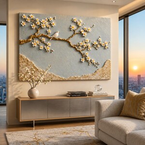 May include: A rectangular wall art piece featuring a textured light blue background with a raised gold branch adorned with white flowers and a small white bird. The bottom section of the artwork displays a textured gold landscape element.