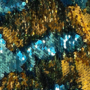 May include: Close-up of a fabric with a shimmering, iridescent texture. The fabric is made of small, overlapping sequins in shades of blue, green, and gold.
