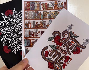 May include: Three art prints with different designs. One black print features white text and red floral accents. A second print depicts a detailed bookshelf illustration. The third print has the text "All for Me" with floral and figure accents.