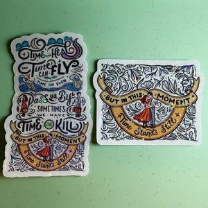 May include: Two stickers with holographic detailing. One features the text "Time can heal and time can fly, time can even pass us by, sometimes we have time to kill, but in this moment time stands still." The other says "But in this moment time stands still."