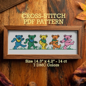 May include: A framed cross-stitch pattern featuring five colorful dancing bears. The bears are blue, green, yellow, orange, and pink, with a green grass border. The frame is brown, and the text reads "CROSS-STITCH PDF PATTERN". The size is 14.3" x 4.2".