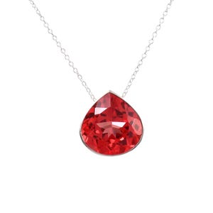 May include: A silver necklace featuring a large, faceted, teardrop-shaped pendant in a vibrant red hue. The pendant is encased in a silver setting and hangs from a delicate silver chain. The design is simple yet eye-catching.