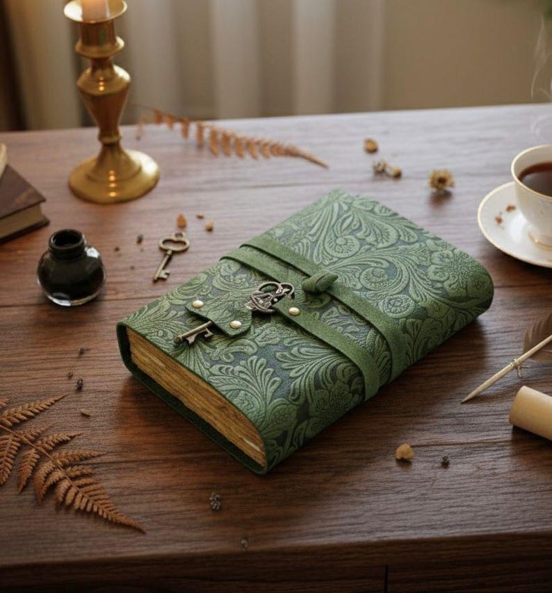 Puede incluir: Diario de cuero verde con un patr&oacute;n floral en relieve y cierre de llave. El diario est&aacute; asegurado con una correa de cuero verde y presenta un dije de llave vintage. Las p&aacute;ginas tienen un tono dorado. Un art&iacute;culo decorativo para escribir o llevar un diario.