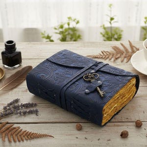 May include: A dark blue leather journal with an embossed floral pattern. The journal is secured with a strap and a decorative key closure. The aged pages have a golden hue, suggesting a vintage aesthetic.