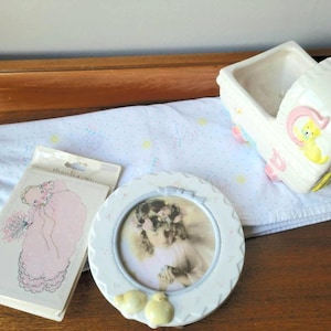 Lief vintage babycadeauset. Babyshower kinderkamerdecoratie. Witte keramische fotolijst met wieg en plantenbak, roze deken en bedankkaartjes
