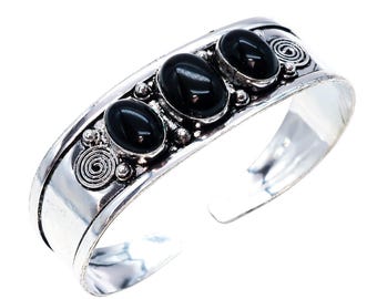 May include: A silver cuff bracelet featuring three oval, black gemstones. The bracelet has a polished finish with decorative spiral and bead accents. The open design allows for easy wear.
