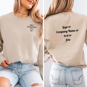 Może przedstawiać: Beżowa bluza z nadrukiem "Logo lub Nazwa firmy lub tekst lub foto" z przodu i z tyłu. Top z długim rękawem jest pokazany na osobie noszącej niebieskie dżinsowe szorty.