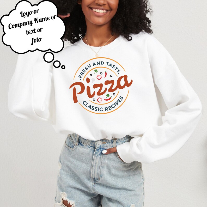 Może przedstawiać: Biała bluza z okrągłym wzorem pizzy. Projekt zawiera słowa "FRESH AND TASTY" i "Pizza" w kolorze brązowym, z ilustracjami dodatk&oacute;w do pizzy. Zawiera r&oacute;wnież słowa "CLASSIC RECIPES".