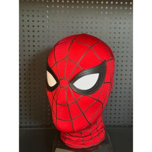 May include: A red Spider-Man mask with black webbing and white eye lenses. The mask covers the entire head and neck, with a textured fabric and a detailed design.