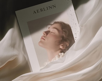 Puede incluir: Una revista con la palabra "AERLINN" impresa en la parte superior. La revista presenta un retrato de una mujer con los ojos cerrados. La revista está rodeada de tela blanca.