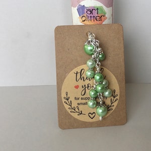 May include: A green pearl charm with a silver chain and a thank you tag that says "Thank you for supporting my small business".