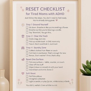 May include: A framed print with a light wood finish displays a checklist titled "RESET CHECKLIST for Tired Moms with ADHD." The text is in a soft, feminine font, with floral accents. The checklist includes steps for grounding, clearing trash, laundry, and resetting a surface.