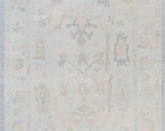 May include: Cream-colored rectangular rug with an intricate, faded floral pattern in muted tones of blue, peach, and olive green. The design features a central medallion and border details, creating a vintage aesthetic.