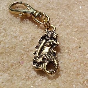 May include: Gold-toned mermaid charm with a detailed design, attached to a gold-toned split ring keychain.