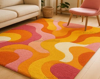 May include: A colorful area rug with a retro design. The rug features a wavy pattern in shades of orange, yellow, pink, and white. The rug is placed on a hardwood floor, and the room includes a sofa, chair, and plants.