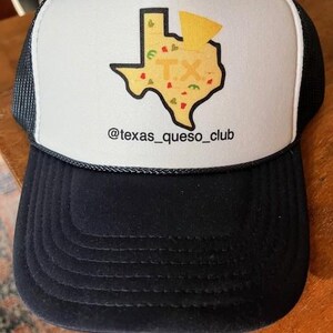 May include: A trucker hat with a white front panel featuring a graphic of the state of Texas filled with food imagery and the letters "TX". The hat has a black brim and mesh back, with the text "@texas_queso_club" below the graphic.