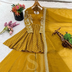 May include: Mustard yellow Indian suit set. The set includes a long-sleeved top with embroidered sleeves and a flared skirt, and a matching sheer scarf. The top has a keyhole back and is decorated with white polka dots.
