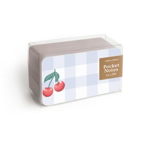 May include: A set of pocket notes in a clear plastic box. The notes have a light blue gingham pattern with a cherry illustration. The label reads "INKLINGS Pocket Notes Set of 50".