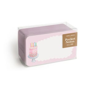 May include: A pink box of 50 birthday-themed pocket notes with a pink and white cake with candles on a white stand. The box has a gold label that says "Inkling's Pocket Notes Set of 50".