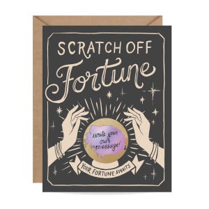 Könnte beinhalten: Eine Grußkarte mit schwarzem Hintergrund und den Worten "SCRATCH OFF Fortune" in weißer Schrift. Die Karte zeigt eine Kristallkugel mit dem Text "write your own message!" und dem Satz "YOUR FORTUNE AWAITS" auf einem Banner.