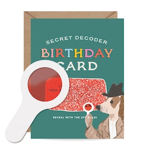 May include: A birthday card with a magnifying glass, featuring the text "SECRET DECODER BIRTHDAY CARD". The card has a teal background and a brown envelope. A cartoon dog detective holds a magnifying glass.