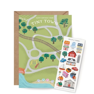 May include: A greeting card with a map of Tiny Town, featuring roads, trees, and a playground. A sticker sheet with town-themed illustrations, including buildings, vehicles, and a bank, is next to the card. The card is in a brown envelope.