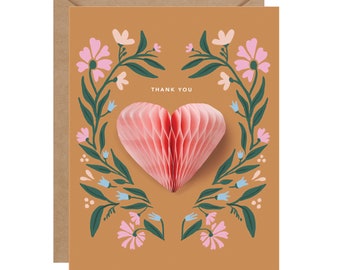 May include: A thank you card with a pop-up heart surrounded by a floral wreath. The heart is pink and the flowers are pink, blue, and green.