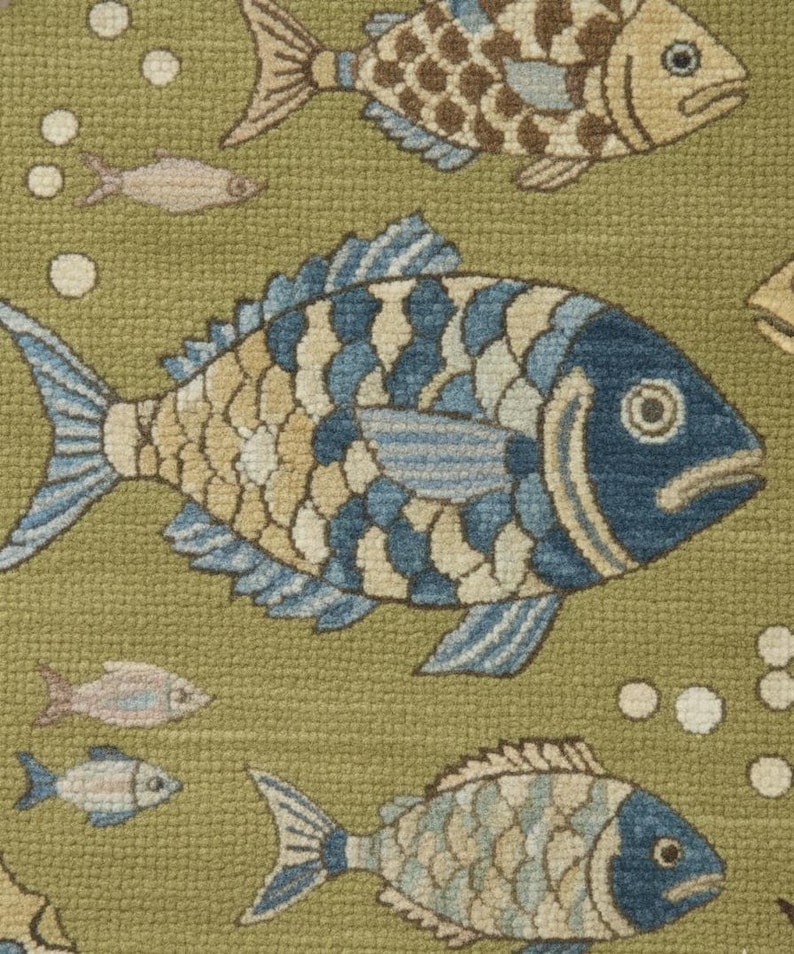 May include: A close-up of a green rug with a repeating pattern of fish. The fish are in shades of blue, tan, and brown, with white bubbles scattered throughout. The fish have detailed scales and fins, creating a textured appearance.
