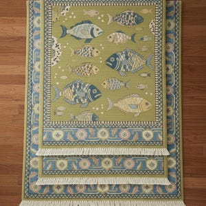 May include: Three rectangular rugs with a fish pattern. The rugs have a green background with various fish designs in blue, tan, and white. The borders are blue with floral patterns and white fringe.
