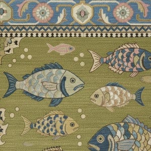 May include: A green rug with a repeating pattern of fish in shades of blue, tan, and pink. The rug has a decorative border with floral and geometric designs in blue, pink, and green. The rug's fringe is a light beige color.