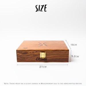 May include: A rectangular wooden box with a compass rose design on the lid. The box is 8.27 inches long, 6.3 inches wide, and 2.05 inches high. It has a gold-colored clasp and the text "Okasan".