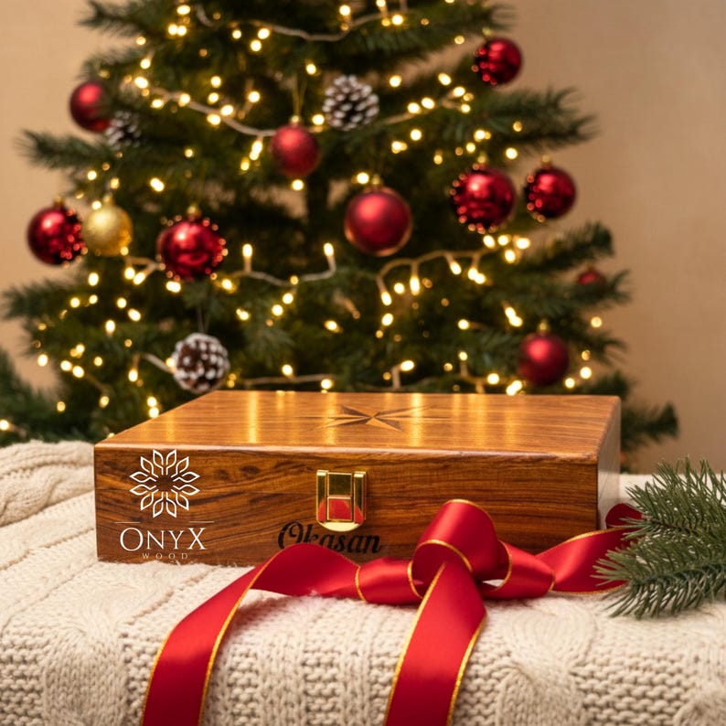 May include: A rectangular wooden box with a polished brown grain finish, featuring a gold-colored metal latch, a star-shaped inlay on the lid, and the text ONYX WOOD and Okasan printed on the front, accented by a red ribbon and a pine branch.