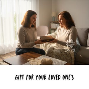 May include: A wooden box with a starburst design on the lid is being presented between two people. The box is dark brown with a gold clasp. The text "GIFT FOR YOUR LOVED ONE'S" is at the bottom of the image.