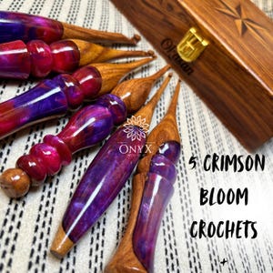 May include: A collection of crochet hooks with crimson and purple resin handles and wooden shafts. The image includes a wooden box with a gold clasp and the text "5 Crimson Bloom Crochets". The Onyx Wood logo is also visible.