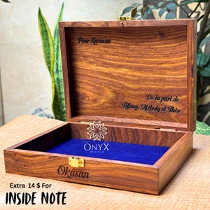 May include: Open wooden box with a blue velvet interior. The box is engraved with the words "Pour Kazasan", "Okasan", and "De la part de Tiffany, M&eacute;lody et Th&eacute;o". The box has a gold-colored clasp and the Onyx Wood logo.