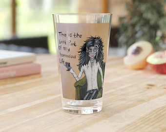 May include: A clear glass with a printed design featuring a cartoon vampire holding a drink. The text on the glass reads "This is the best part of my horrendous Life."