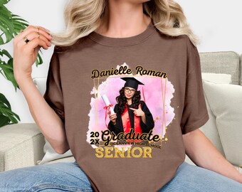 May include: A brown t-shirt featuring a graduation design. The design includes the name "Danielle Roman", the word "Graduate", and "Oceanview High School Senior". The design also includes a photo of a graduate in a cap and gown.